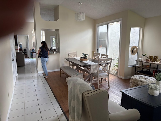 dining area with light wood-style flooring, a textured ceiling, lofted ceiling, and baseboards