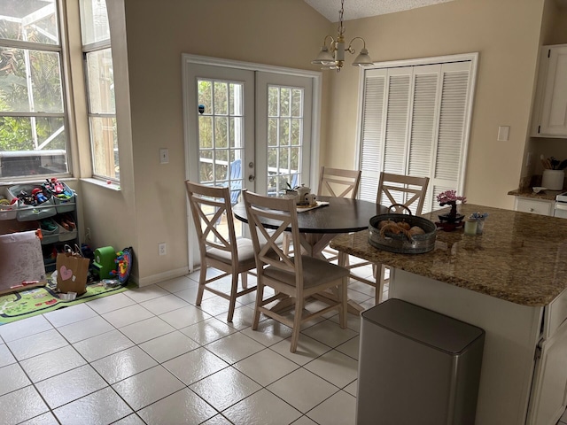 dining area with a chandelier, a wealth of natural light, french doors, and light tile patterned floors