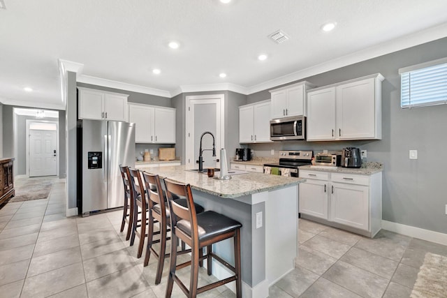 6449 NW Castlebrook Ave, Port Saint Lucie, FL 34983 - kitchen featuring crown molding, appliances with stainless steel finishes, a sink, a kitchen bar, and visible vents