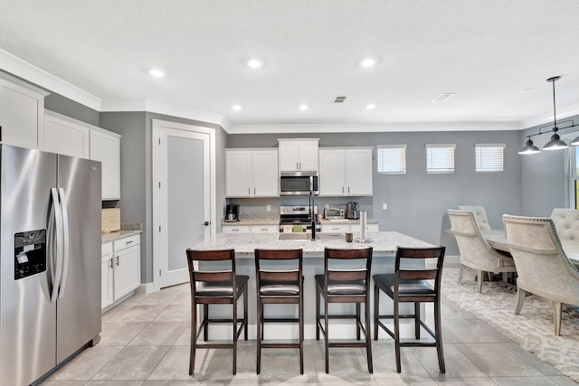 6449 NW Castlebrook Ave, Port Saint Lucie, FL 34983 - kitchen featuring a kitchen island with sink, stainless steel appliances, white cabinetry, visible vents, and ornamental molding