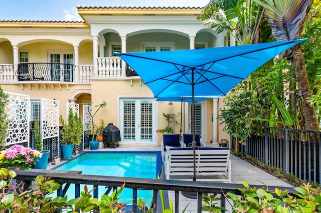 back of house featuring a patio, a balcony, stucco siding, french doors, and fence