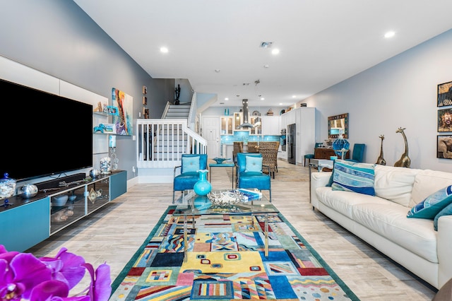 living area featuring visible vents, recessed lighting, light wood-type flooring, and stairway