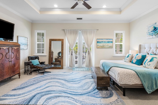 bedroom with a raised ceiling, access to outside, multiple windows, and carpet