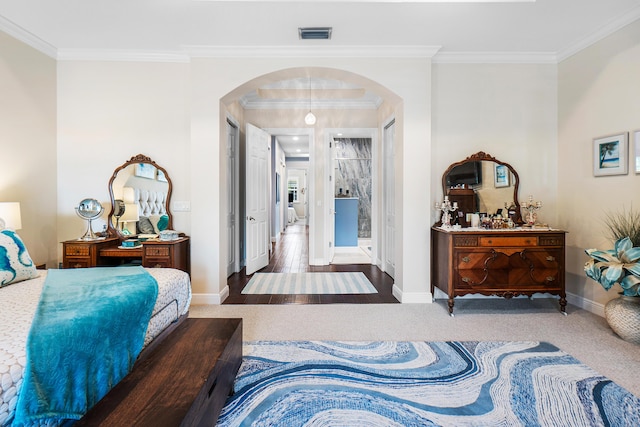 bedroom with baseboards, ornamental molding, carpet flooring, visible vents, and arched walkways