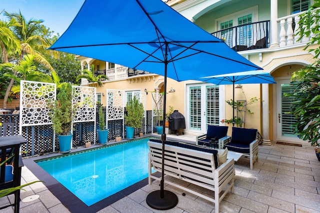 outdoor pool with french doors, fence, a patio, and a grill