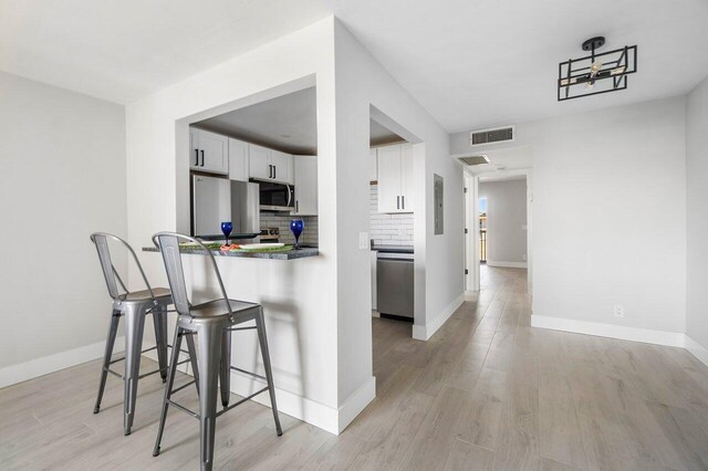 400 Village Green Cir W Unit 310, Palm Springs, FL 33461 - kitchen featuring a sink, dark stone counters, stainless steel appliances, white cabinetry, and backsplash
