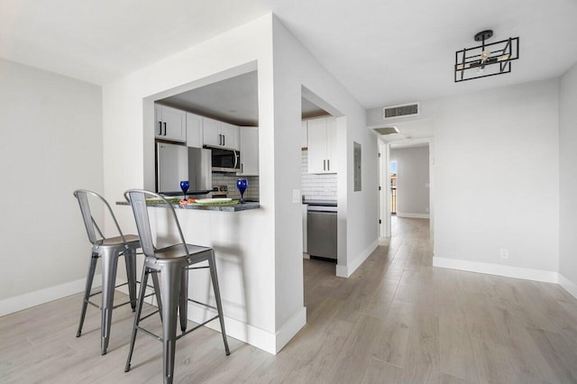 400 Village Green Cir W Unit 310, Palm Springs, FL 33461 - kitchen with tasteful backsplash, visible vents, a kitchen breakfast bar, white cabinets, and appliances with stainless steel finishes