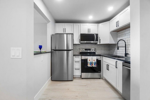 400 Village Green Cir W Unit 310, Palm Springs, FL 33461 - kitchen with a sink, stainless steel appliances, decorative backsplash, dark countertops, and light wood-style floors
