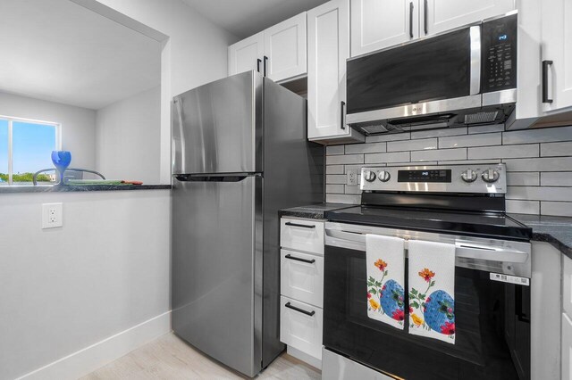 400 Village Green Cir W Unit 310, Palm Springs, FL 33461 - kitchen featuring stainless steel dishwasher, baseboards, a sink, dark stone countertops, and white cabinets