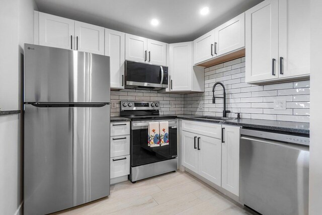 400 Village Green Cir W Unit 310, Palm Springs, FL 33461 - kitchen with stainless steel appliances, tasteful backsplash, light wood-style flooring, white cabinetry, and baseboards