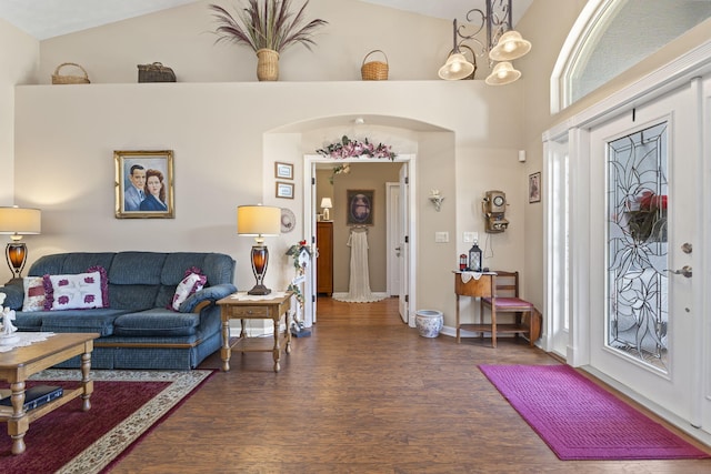 foyer with a notable chandelier, baseboards, high vaulted ceiling, arched walkways, and wood finished floors