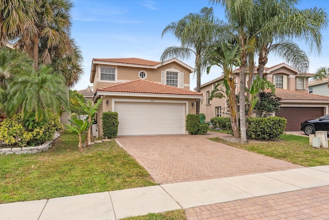 mediterranean / spanish home with a front yard, a garage, a tile roof, stucco siding, and decorative driveway