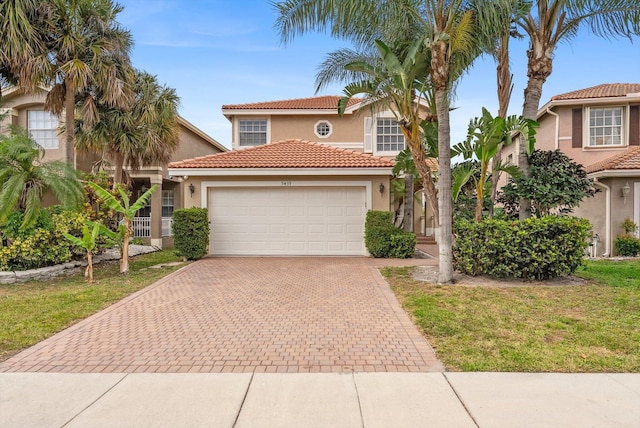 mediterranean / spanish-style home with an attached garage, a tiled roof, stucco siding, and decorative driveway