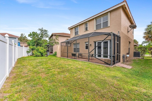 back of house with a lanai, a yard, a fenced backyard, and stucco siding