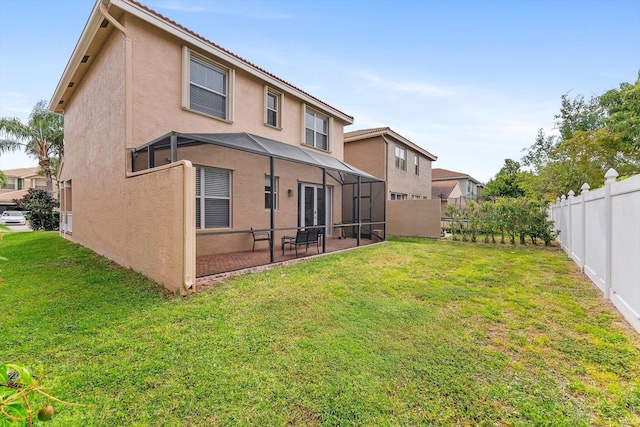 back of house featuring stucco siding, a fenced backyard, a lanai, and a lawn