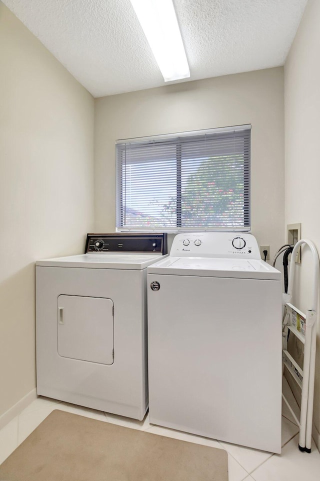 laundry room with washer and dryer, light tile patterned floors, a textured ceiling, and laundry area