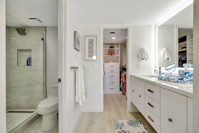 bathroom with a sink, toilet, double vanity, wood finished floors, and a stall shower