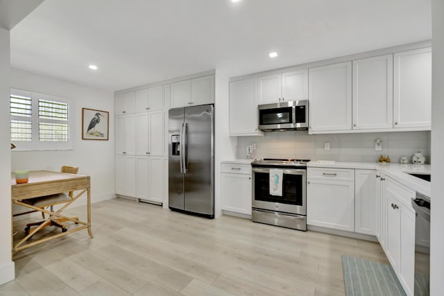kitchen featuring decorative backsplash, recessed lighting, light countertops, light wood-type flooring, and stainless steel appliances