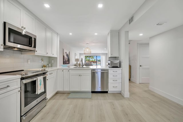 kitchen with visible vents, appliances with stainless steel finishes, a sink, light wood finished floors, and white cabinetry