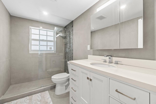 bathroom featuring visible vents, toilet, tiled shower, and vanity