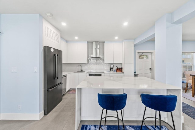 kitchen with wall chimney exhaust hood, modern cabinets, freestanding refrigerator, a breakfast bar, and stainless steel dishwasher
