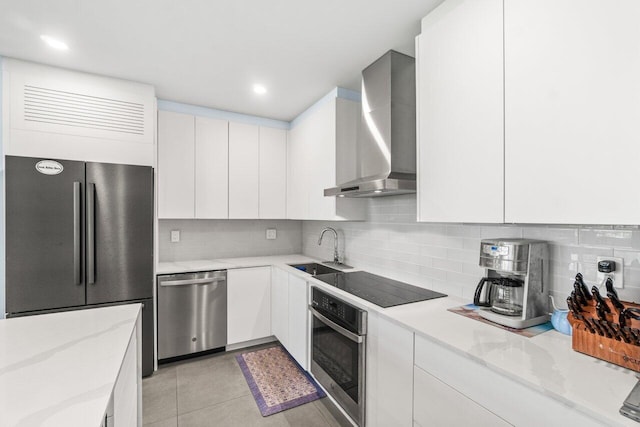 kitchen with white cabinets, wall chimney exhaust hood, modern cabinets, a sink, and appliances with stainless steel finishes