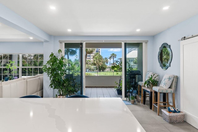 tiled dining area featuring a barn door and recessed lighting