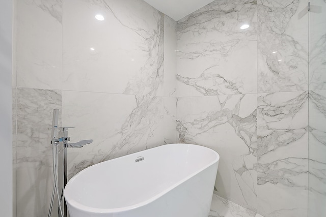 full bathroom featuring a freestanding tub, tile walls, and marble finish floor