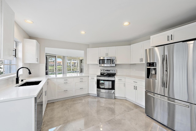 kitchen featuring backsplash, stainless steel appliances, a sink, and light countertops