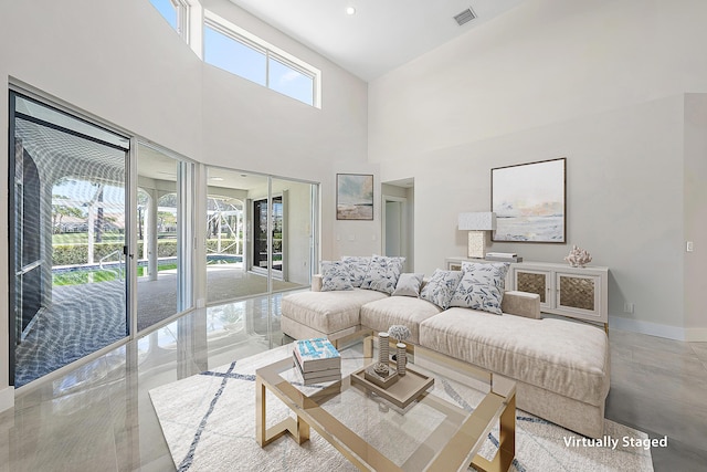 living area with a towering ceiling, baseboards, and visible vents