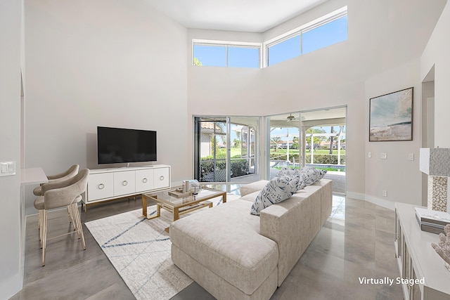 living room featuring baseboards, a high ceiling, and concrete flooring