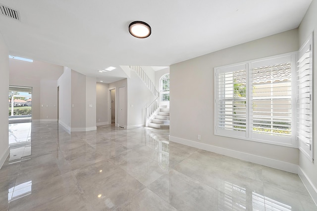 unfurnished room featuring baseboards, visible vents, and plenty of natural light