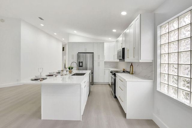 kitchen with stainless steel appliances, a sink, tasteful backsplash, vaulted ceiling, and light wood-style floors