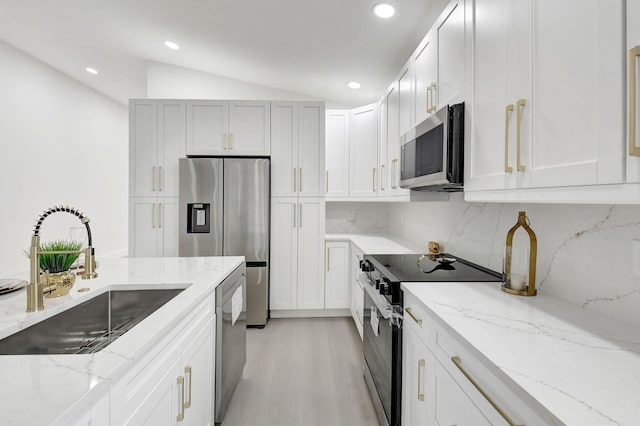 kitchen featuring a sink, backsplash, lofted ceiling, appliances with stainless steel finishes, and recessed lighting