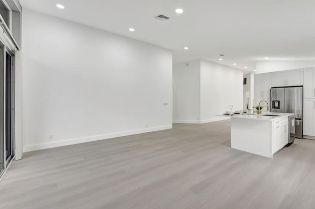 kitchen featuring recessed lighting, visible vents, a sink, light wood-type flooring, and stainless steel fridge