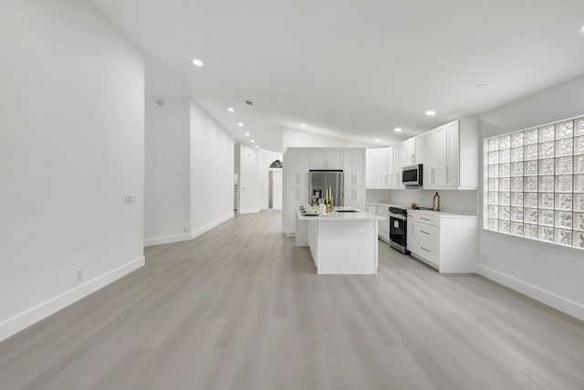 kitchen with a sink, open floor plan, light countertops, appliances with stainless steel finishes, and recessed lighting