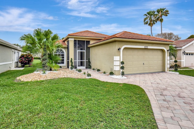mediterranean / spanish-style house featuring a tiled roof, a front lawn, a garage, stucco siding, and decorative driveway