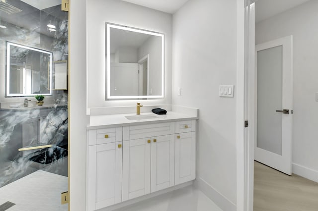 full bathroom featuring wood finished floors, a marble finish shower, vanity, baseboards, and visible vents