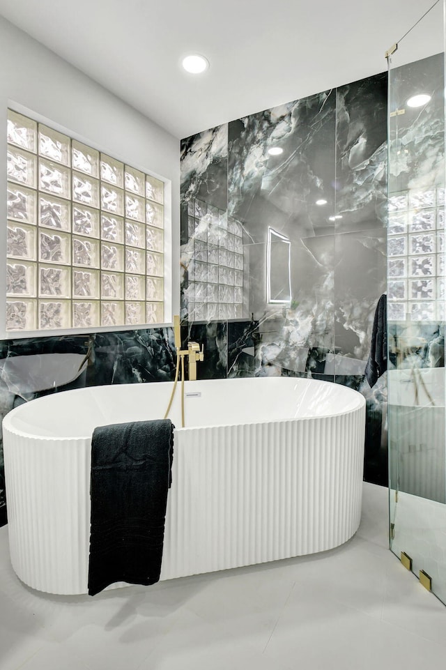full bathroom with tile walls and a freestanding tub