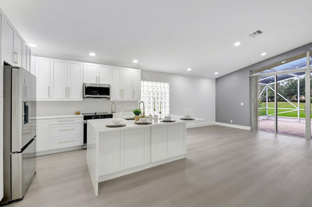 kitchen with appliances with stainless steel finishes, light wood-style flooring, baseboards, white cabinetry, and visible vents