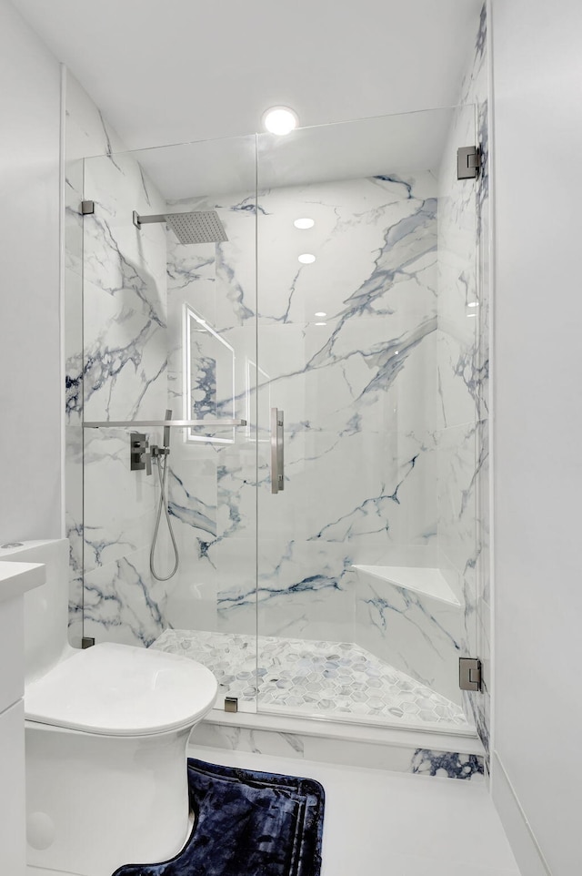 bathroom featuring toilet, a marble finish shower, and recessed lighting