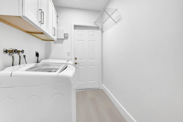 laundry room with cabinet space, light wood-style floors, washing machine and dryer, and baseboards