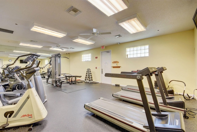 exercise room with ceiling fan, a textured ceiling, and visible vents