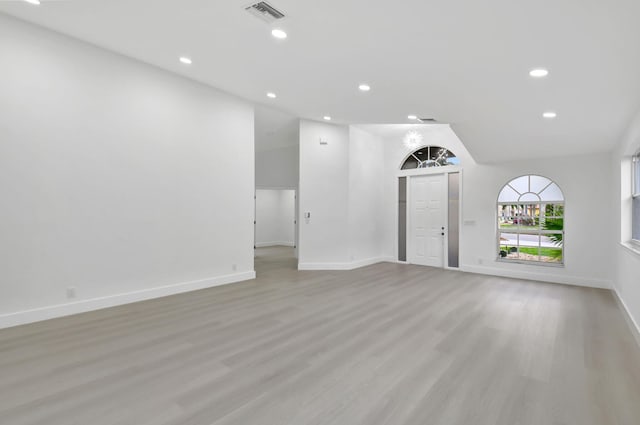 unfurnished living room with light wood-style flooring, baseboards, lofted ceiling, visible vents, and recessed lighting