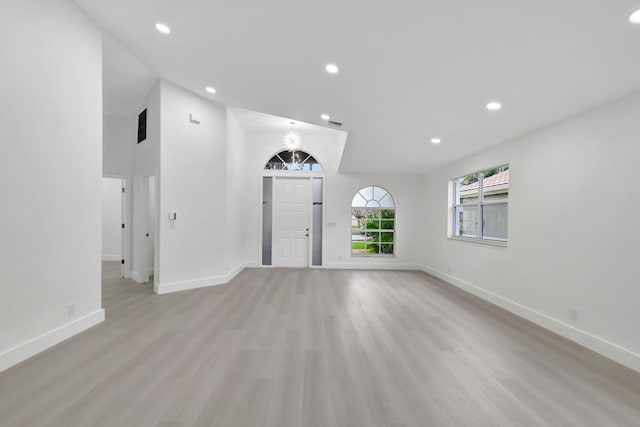 unfurnished living room featuring recessed lighting, light wood-style floors, lofted ceiling, and baseboards