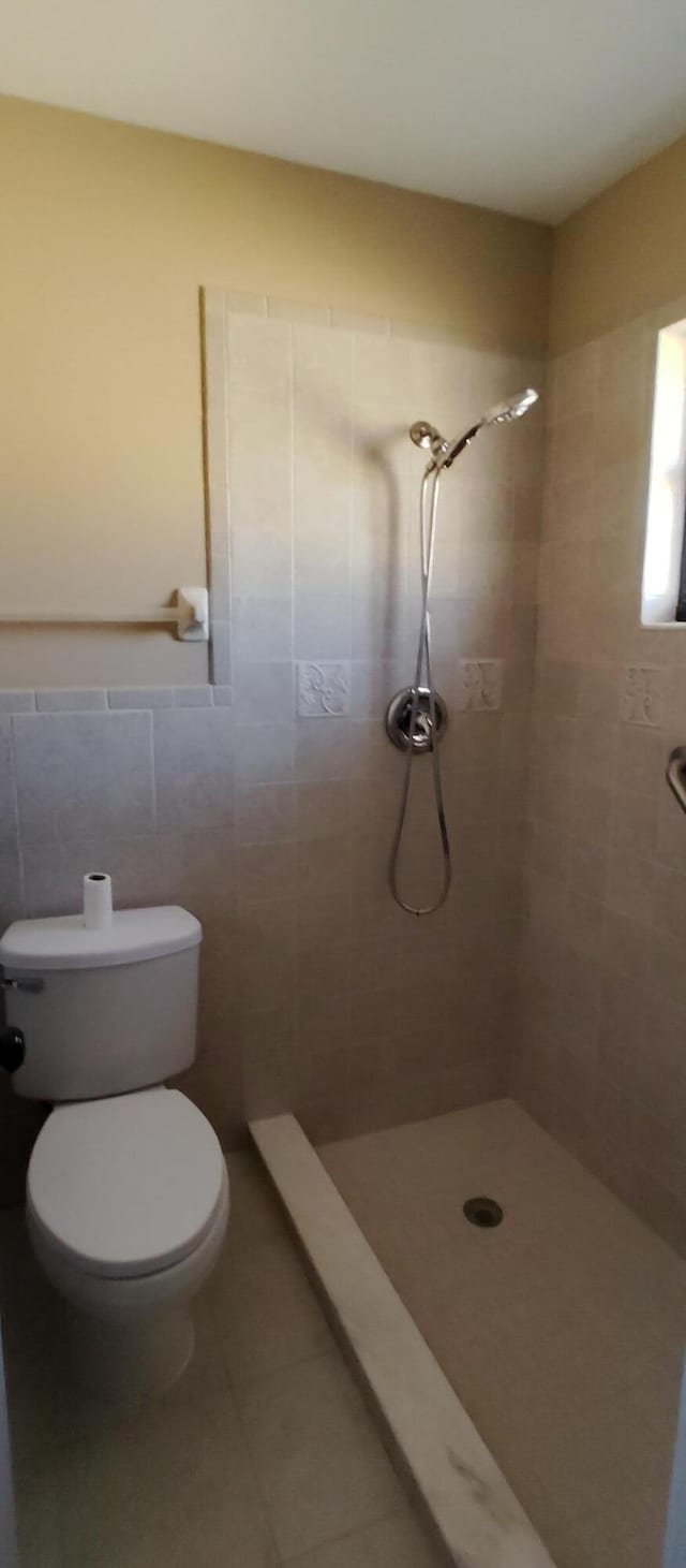 full bathroom with toilet, tile walls, tile patterned floors, and a stall shower
