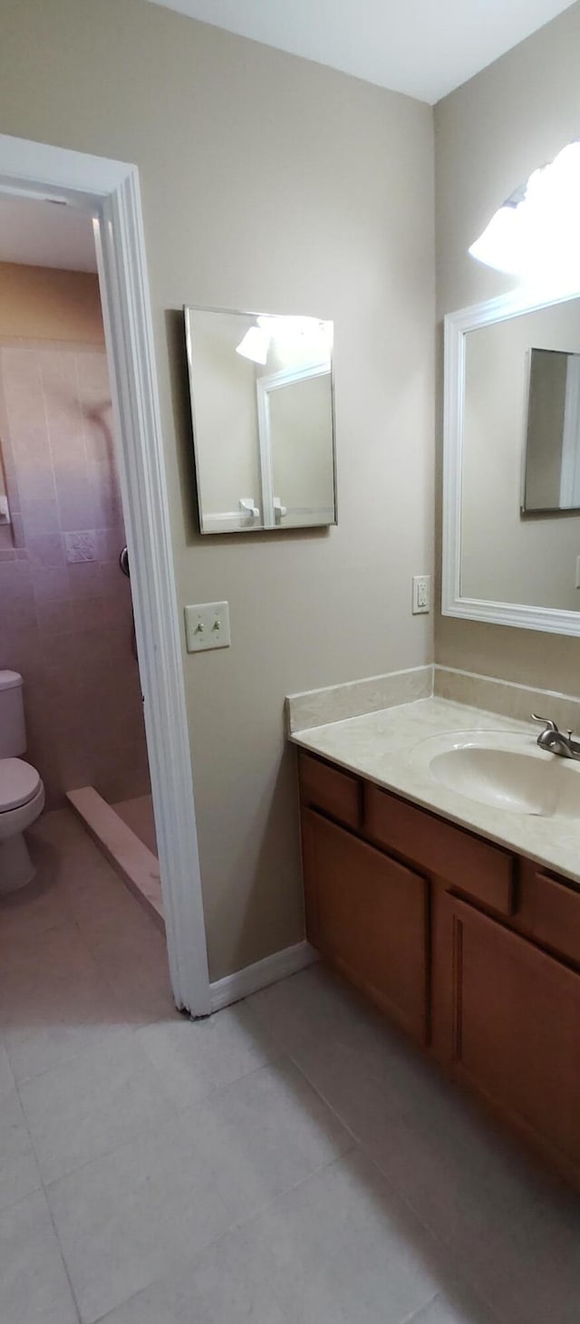 full bath featuring tile patterned floors, vanity, a tile shower, and toilet