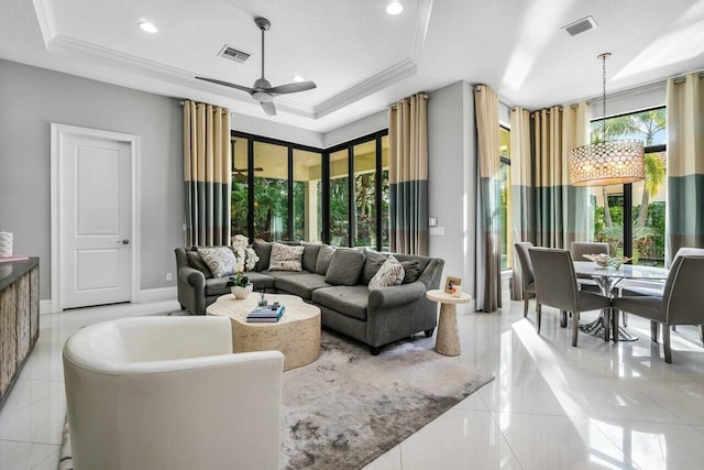 living room featuring a tray ceiling, ornamental molding, a ceiling fan, and visible vents