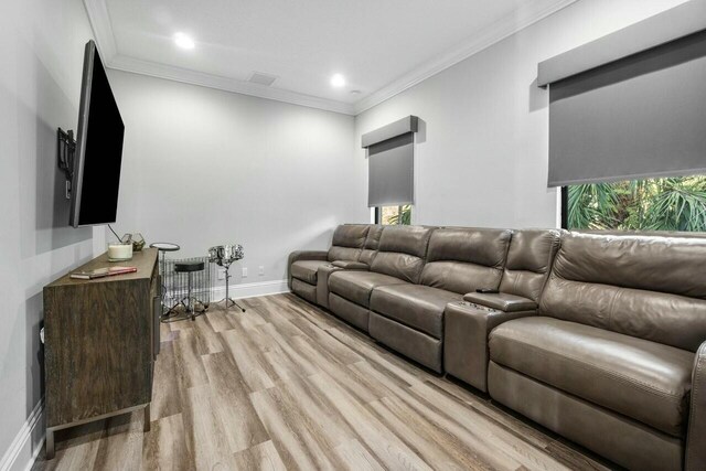 living area with a wealth of natural light, light wood-style flooring, ornamental molding, visible vents, and baseboards