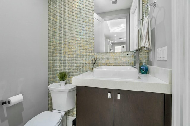 bathroom with toilet, decorative backsplash, vanity, and tile walls